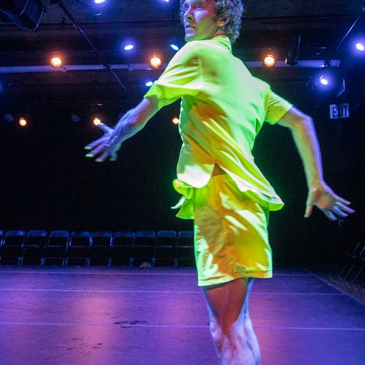 Dancer wearing neon yellow shirt and shorts performing twisting movement